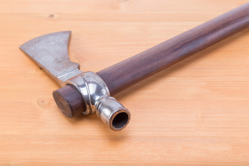 Traditional tomahawk hand ax used by the native american indians displayed on a natural oak wood brown table - back side