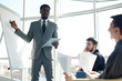 © pressmaster - Portrait of successful African businessman pointing at whiteboard  during presentation meeting