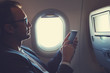 © astrosystem - Man using smartphone in the airplane.