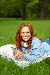 Canvas Print - frau liegt auf einer wiese und hört musik mit ihrem handy