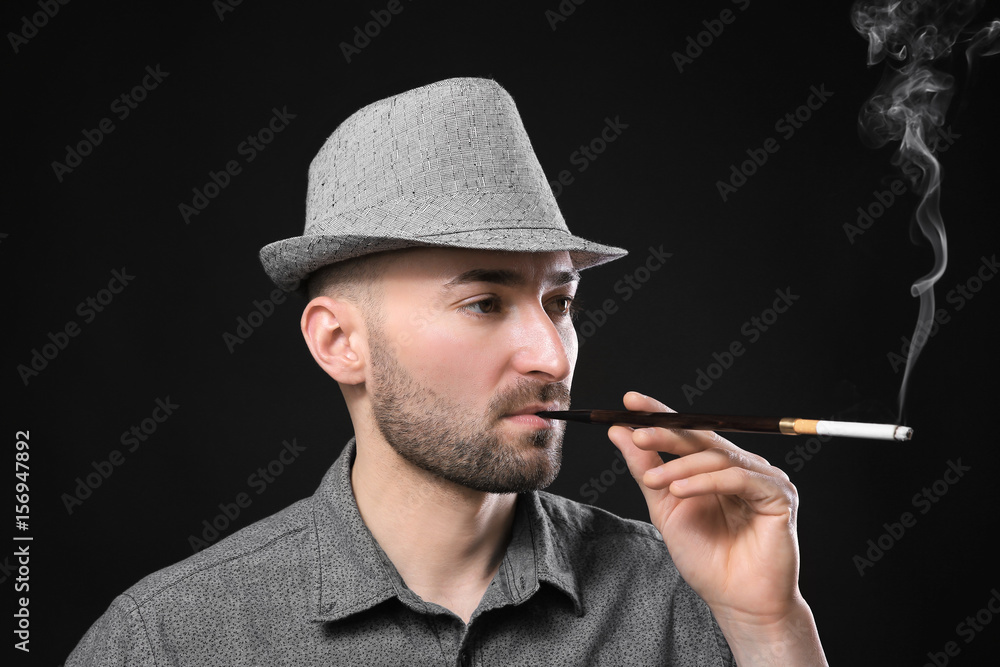 Handsome man smoking cigarette on dark background