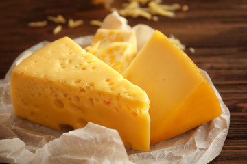 Wall Mural - Parchment with different types of cheese on wooden table