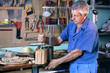 © angellodeco - cabinetmaker carving wood with screw clamp in workbench / carpenter fixing the wood with a clamp for sawing