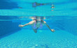 © zilvergolf - Underwater shot of young woman diving into the swimming pool.