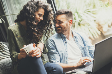 Wall Mural - Happy cute couple in love with laptop  drinking coffee and smiling