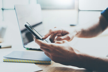 Wall Mural - Closeup view of Businessman pointing finger on modern smartphone.Coworker working at sunny office at office.Visual effects.Blurred background.