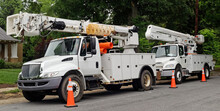 Front And Side View Of Parked Communication Utility Trucks In Residential Neighborhood. Horizontal.