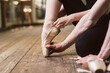 © o_lypa - Young ballerina or dancer girl putting on her ballet shoes on the wooden floor. Male ballet dancer helps puttiing on. close-up.