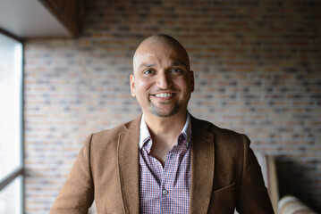 Portrait of happy handsome indian business man, smiling, confident and friendly indoors.