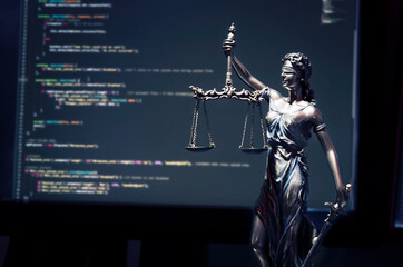 Justice statue with code on monitor device in background