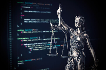 justice statue with code on monitor device in background