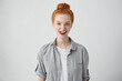 Pretty ginger woman with blue eyes and fleckles wearing casual shirt having fun while touching her teeth with tongue having happy expression posing in studio. People, body language and emotions