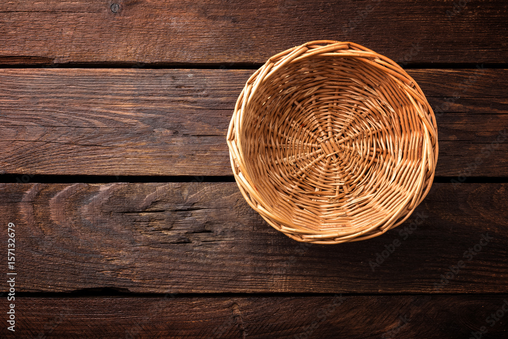 Empty wicker basket on a wooden background, top view - obrazy, fototapety, plakaty 