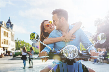 Beautiful young couple riding scooter together.