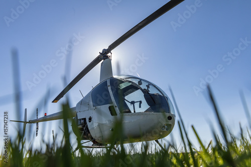 Zdjęcie XXL Mały Robinson R22 lekki użyteczność helikopter parkujący na trawa lotnisku. Jeden z najpopularniejszych lekkich śmigłowców na świecie z dwoma ostrzami i jednym silnikiem