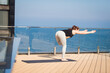 © serejkakovalev - sport woman doing stretching yoga exercise on hotel roof with wooden floor stand on yoga mat