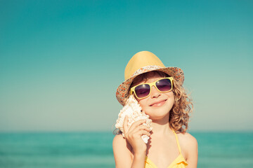 Poster - Happy child listen seashell on the beach