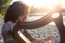 Beautiful Curly Hair Woman Playing The Harp