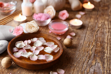 Wall Mural - Bowl with water and rose petals on wooden table