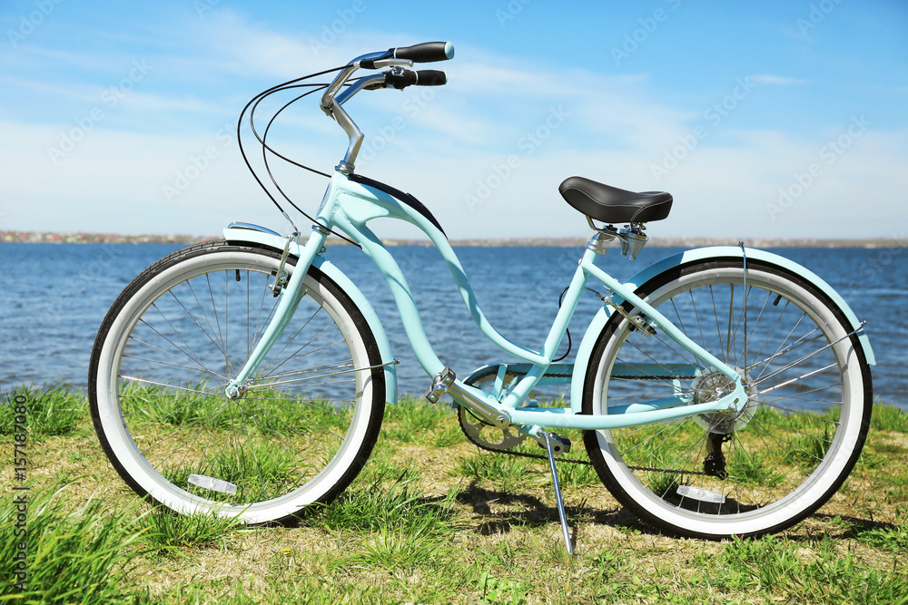 Blue bicycle standing on grass near river
