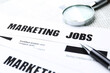 © Africa Studio - Paper sheet with text MARKETING JOBS, pen and magnifier, closeup