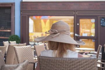 Wall Mural - femme blonde avec un chapeau assise seule à une terrasse de café 