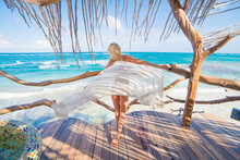 Woman Waving Dress In The Wind Overlooking A Tropical Ocean