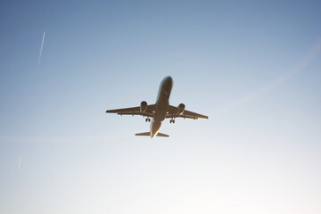 Silhouette of airplane sitting down above fields on soft sunrise in blue clear sky close to aeroport.