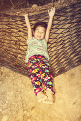 Wall Mural - Cheerful child enjoying and relaxing in hammock, outdoor on summer day.