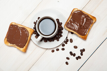 Wall Mural - cup of coffee and toast with chocolate on a white wooden table