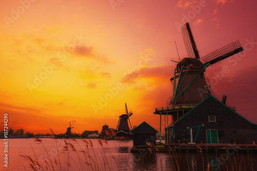 Fotografie, Obraz Traditional Dutch windmills on the canal bank at warm sunset light in Netherland