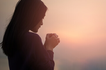 christian woman praying worship at sunset. hands folded in prayer. worship god with christian concep