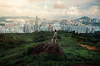 man traveler standing on top of cliff in mountain and enjoying view of Hong Kong