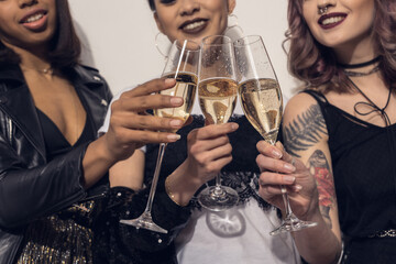 young smiling multiethnic girls clinking with glasses of champagne at party