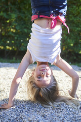 active young child cute girl climbing on playground. upside down. handstand. children summer activit