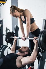 Wall Mural - Athletic young man and woman training with dumbbell in gym