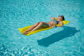 A woman in the pool floats on a blown mattress