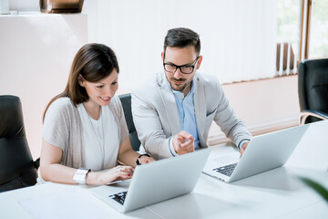 Business people working together on laptop in office at desk