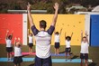 Coach teaching exercise to school kids