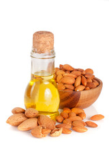 Wall Mural - Bottle of almond oil and almonds in a wooden bowl isolated on white background