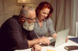 © LIGHTFIELD STUDIOS - portrait of husband and wife sitting at the table and using laptop at home┬а
