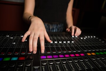 Mid-section of female audio engineer using sound mixer