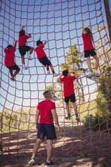 Wall Mural - trainer instructing kids in net climbing