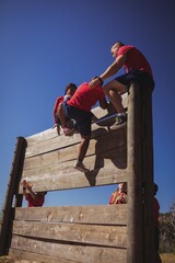 Wall Mural - trainer assisting kids to climb a wooden wall