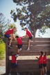 Trainer assisting kids to climb a wooden wall