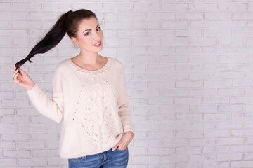 Poster - portrait of beautiful woman playing with her hair and space over white brick wall