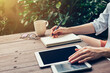 © tortoon - Woman hand writing note pad on wood table in coffee shop.