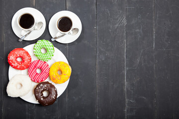 Wall Mural - Two cups with coffee and donuts on a black wooden table