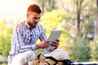 © lordn - Young man with tablet computer working in the park