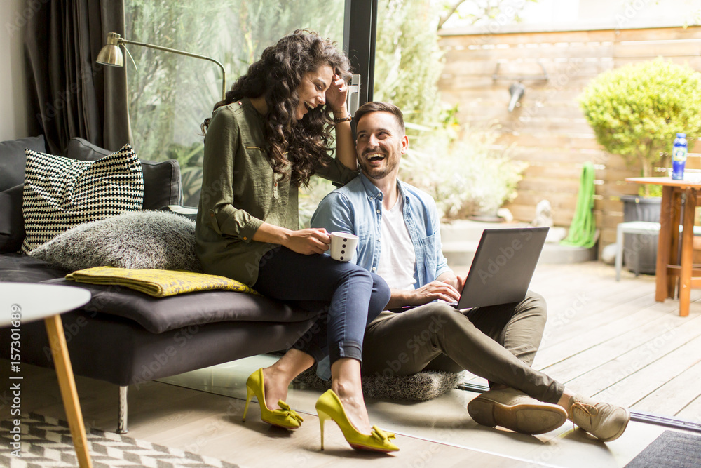 Happy cute couple in love with laptop  drinking coffee and smiling